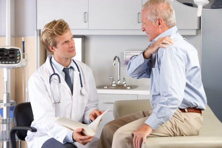 Doctor examining patient with shoulder pain